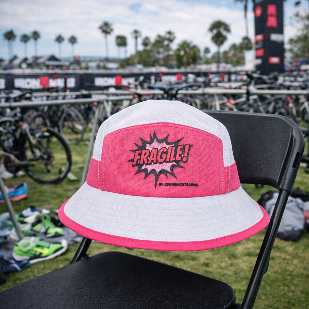 Bob FRAGILE! XT rose et blanc posé en parc de transition Ironman, accessoire sport et lifestyle Xperience Training
