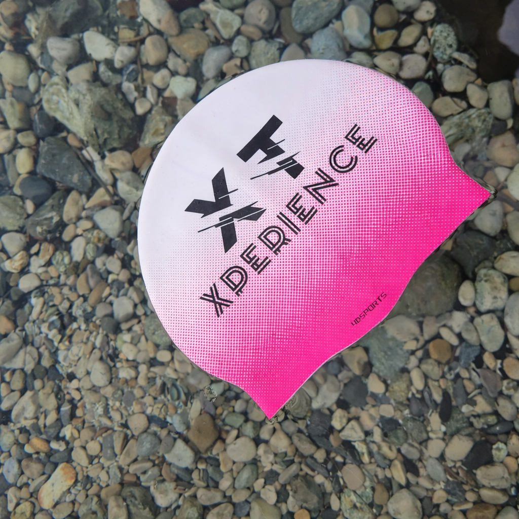 Bonnet de natation XT rose et blanc, Xperience Training, posé dans l’eau pour natation et eau libre