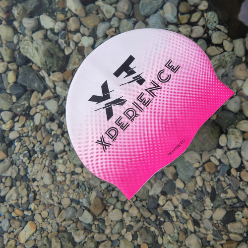Bonnet de natation XT rose et blanc, Xperience Training, posé dans l’eau pour natation et eau libre